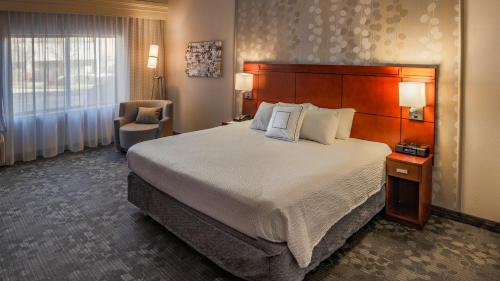 um quarto de hotel com uma cama grande e uma cadeira em Courtyard by Marriott Norman em Norman