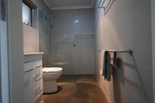 a white bathroom with a toilet and a shower at Moonta Bay Holiday Park in Port Moonta