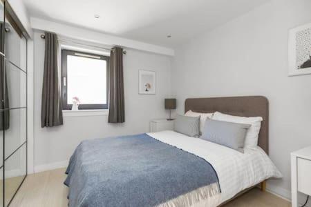 a white bedroom with a large bed and a window at Gorgeous old town Hideaway in Edinburgh
