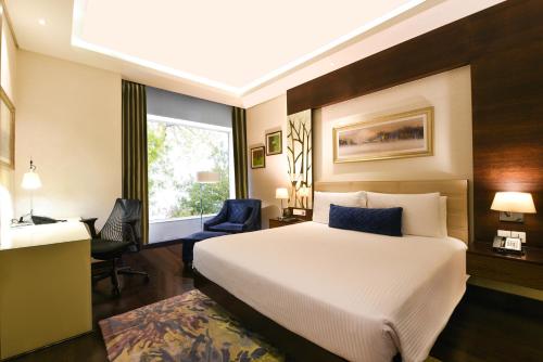 a bedroom with a bed and a desk and a window at DoubleTree by Hilton Gurugram Baani Square in Gurgaon