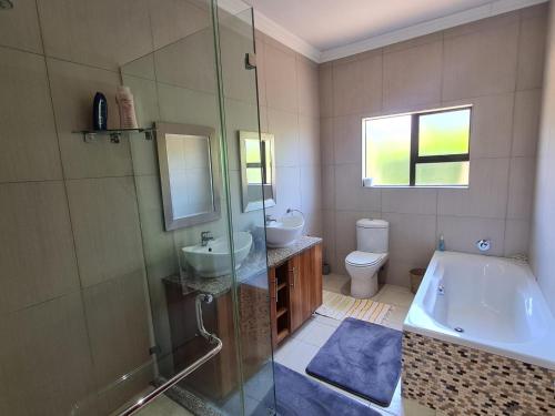 een badkamer met 2 wastafels, een douche en een bad bij 2 Park Lane Pecanwood 4 Bedroom in Hartbeespoort