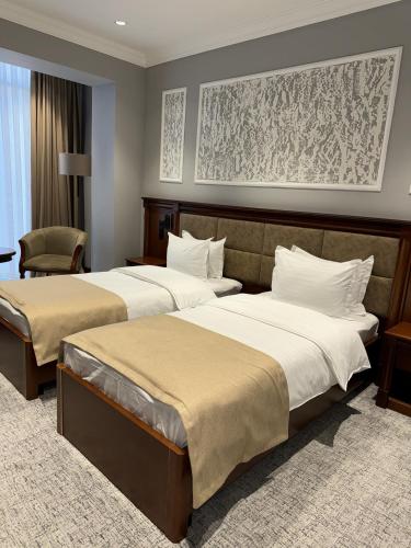 a hotel room with two beds and a chair at Mir Luxe Plaza in Tashkent