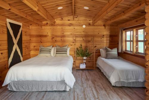 Tenterfield Lodge Caravan Park في تينتيرفيلد: سريرين في غرفة بجدران خشبية
