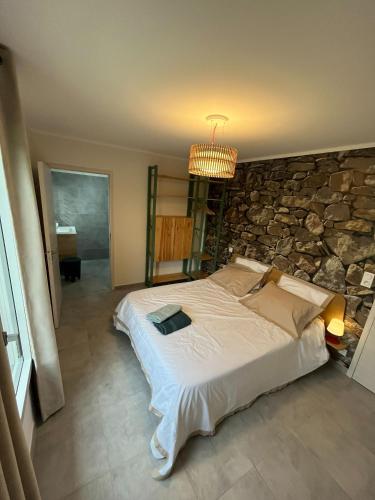 une chambre avec un grand lit avec un mur en pierre dans l'établissement Villa Saint Florent - Terrace and swimming pool, à Santo-Pietro-di-Tenda