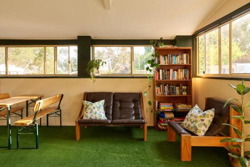 a living room with two leather chairs and a book shelf at Tenterfield Lodge Caravan Park in Tenterfield
