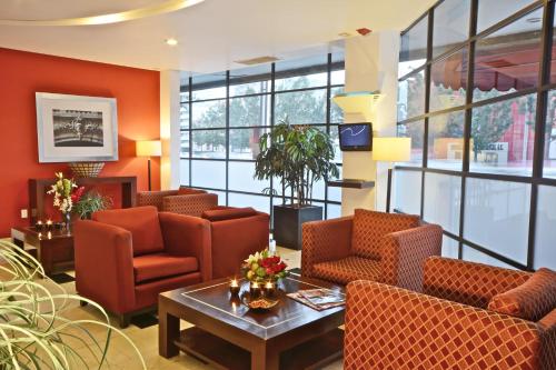 a waiting room with orange chairs and a table at Hotel & Suites PF in Mexico City