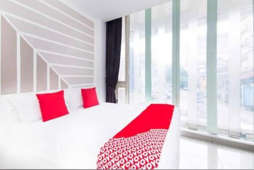 un letto bianco con cuscini rossi in una stanza con finestra di SAND HOTEL a Kuala Lumpur