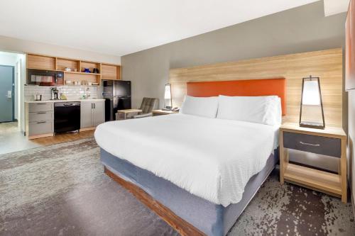 a bedroom with a large bed and a kitchen at Candlewood Suites - Roanoke Airport in Roanoke