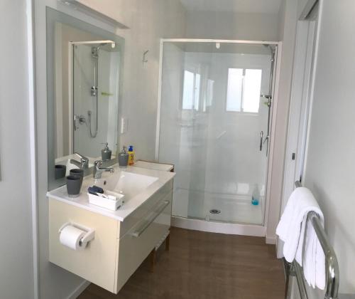 a white bathroom with a shower and a sink at Baywaterviews in Paihia