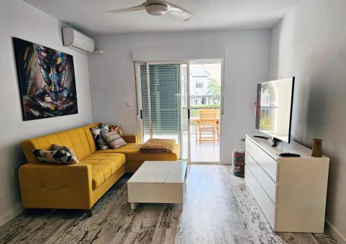 ein Wohnzimmer mit einem gelben Sofa und einem TV in der Unterkunft Casa De Kosma in Torrevieja