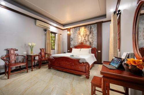 1 dormitorio con 1 cama, mesa y sillas en Nam Hai Hotel en Hanói