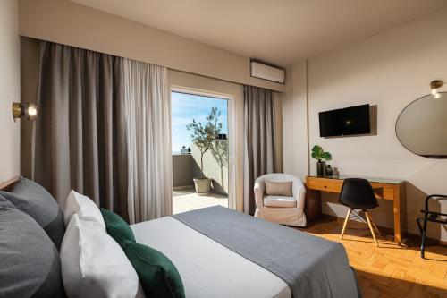 ein Hotelzimmer mit einem Bett, einem Schreibtisch und einem Fenster in der Unterkunft Hotel Delfini in Piräus
