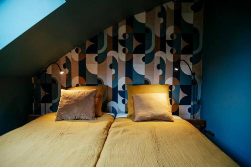 a bed with two pillows on it in a room at Le rétro chic - Grand Duplex pour 6 dans le centre in Liège