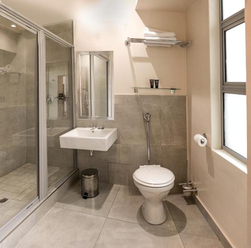 a bathroom with a toilet and a sink and a shower at Parade Hotel in Durban