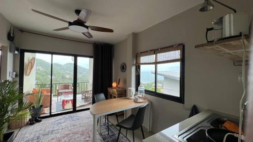 a kitchen with a table with chairs and a balcony at Sunset Hilltop Ocean View 2bd House in Haad Tian