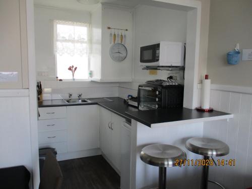 a kitchen with a black counter top and a microwave at High Street Living Motel in Picton