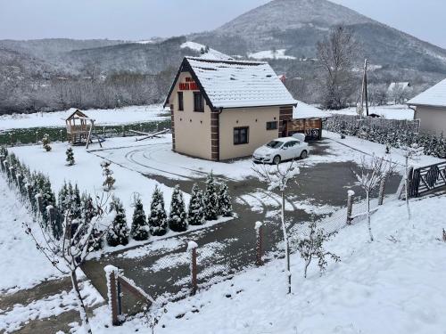 a house with a car parked in the snow at Vila Oaza mira Draganići in Raška