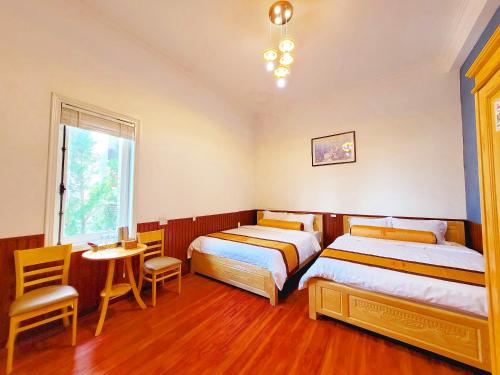 1 dormitorio con 2 camas, mesa y sillas en Villa H Flower Đà Lạt, en Da Lat