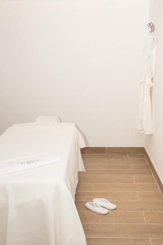 a bedroom with a white bed and a pair of slippers at Almond Hotel - Adults only in Neve Ilan