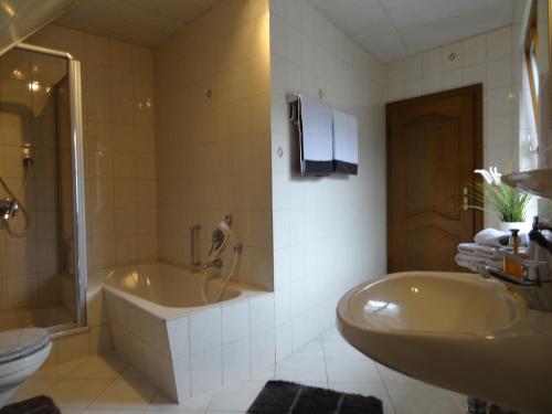 a bathroom with a tub and a sink and a toilet at Ferienhaus van Vliet in Morbach