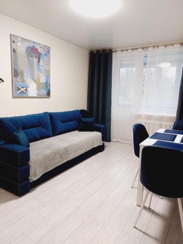 een woonkamer met een blauwe bank en een tafel bij Свежая 2-комнатная квартира в центре in Chmelnytsky