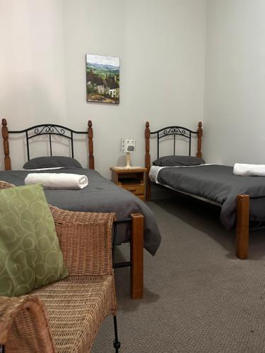 2 Betten in einem Zimmer mit einem Stuhl und einem Sofa in der Unterkunft THE FED AND BED TEMORA in Temora