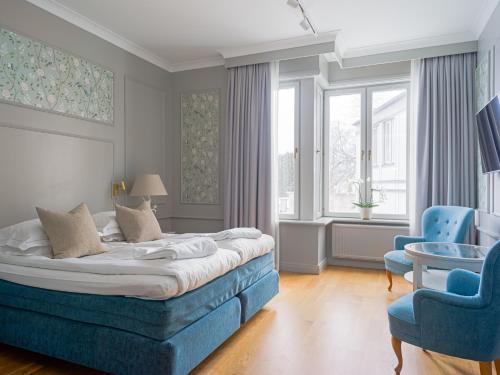 トローサにあるTrosa Stadshotell & Spaのベッドルーム1室(ベッド1台、青い椅子2脚付)