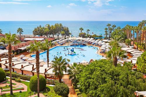 an outdoor swimming pool with umbrellas and the ocean at TUI BLUE Pascha Bay in Konaklı