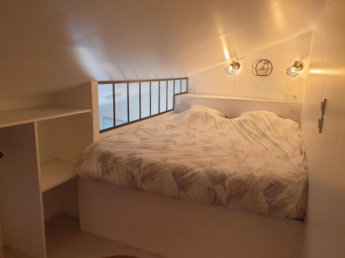 een bed in een kleine kamer met een raam bij Mezza'Nîmes in Nîmes