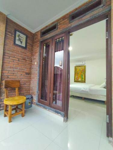 a room with a wooden door and a wooden chair at Pondok Selip Guesthouse in Krambitan