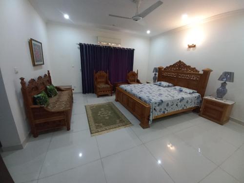 een slaapkamer met een bed en stoelen in een kamer bij DHA 2 House, Islamabad in Islamabad