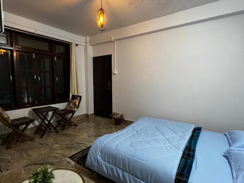 a bedroom with a bed and a table and chairs at EJ’s Frontyard- The Home Cafe & Stay in Kurseong
