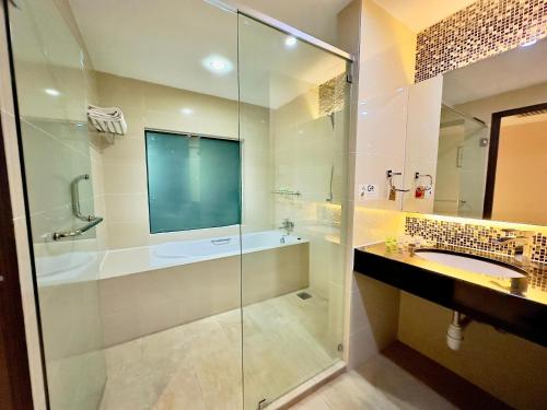 uma casa de banho com uma cabina de duche em vidro e um lavatório. em Kinta Riverfront Hotel & Suites em Ipoh