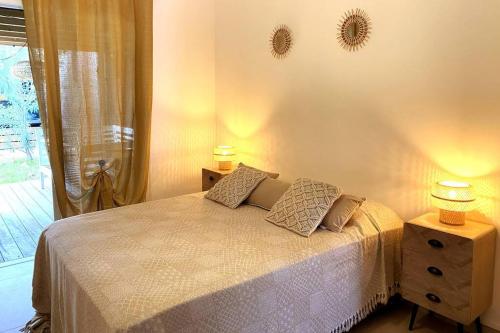 a bedroom with a bed with two lamps and a window at Villa Rosa Palma 10 personnes piscine chauffée à St Gilles les bains in Saint-Paul