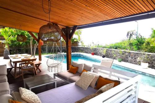 une terrasse avec un canapé, une table et une piscine dans l'établissement Villa Rosa Palma 10 personnes piscine chauffée à St Gilles les bains, à Saint-Paul