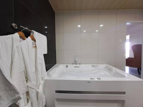 La salle de bains est pourvue d'une grande baignoire et de serviettes blanches. dans l'établissement VIP 2BR Penthouse-Kandi Palace 155sqm w/ Jacuzzi, à Ángeles
