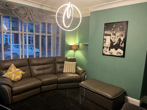 a living room with a brown couch and a chandelier at Two the Manor Born 3 bedroom house in Tynemouth