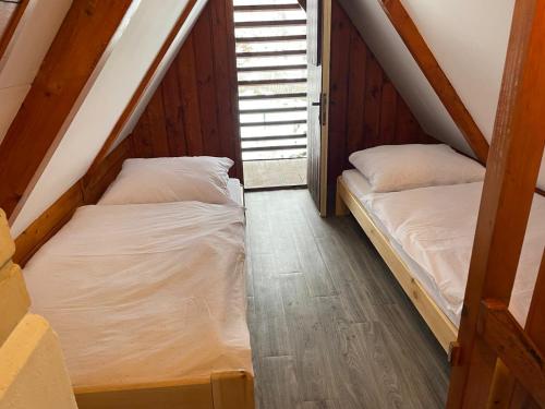 two beds in a attic room with wooden floors at Ubytování Doubice in Doubice