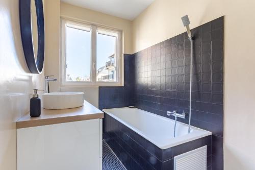 une salle de bain avec une baignoire, un lavabo et une fenêtre dans l'établissement Le Carrousel - Appartement avec studio attenant, à Deauville