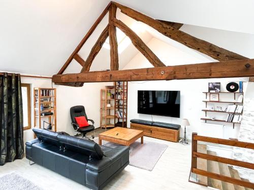 a living room with a black leather couch and a tv at W27B - Alla Prima, Super villa au cœur de Giverny in Giverny