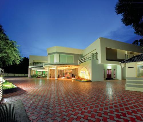 a large white building with a red brick driveway at HOTEL SRIVATSA REGENCY in Pudunagaram