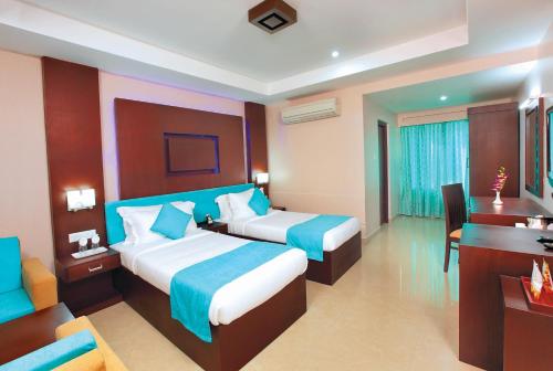 a hotel room with two beds and a desk at HOTEL SRIVATSA REGENCY in Pudunagaram