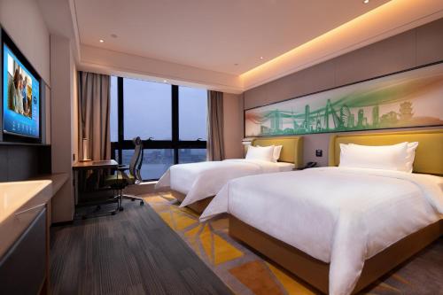 Hampton by Hilton Chengdu Xibo City في تشنغدو: غرفة فندقية بسريرين وتلفزيون بشاشة مسطحة