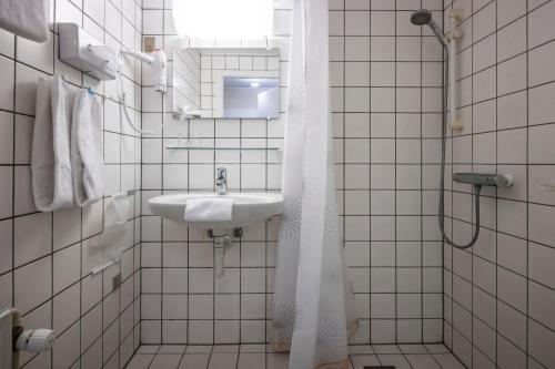 Baño blanco con lavabo y espejo en Hotel Tønderhus en Tønder