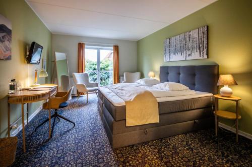 una camera con un grande letto, una scrivania e sedie di Hotel Tønderhus a Tønder