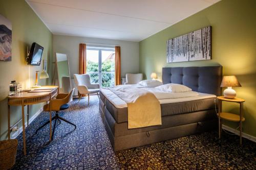 a bedroom with a large bed with a desk and chairs at Hotel Tønderhus in Tønder