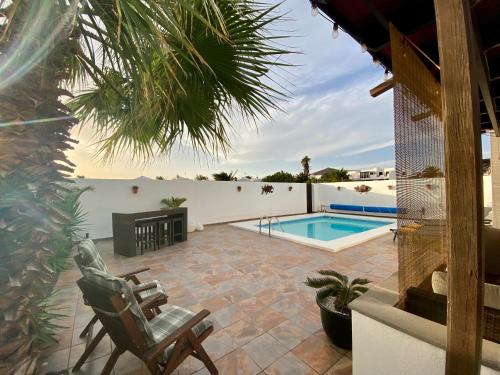 a patio with a chair and a swimming pool at La Mar Poolvilla in Costa Teguise