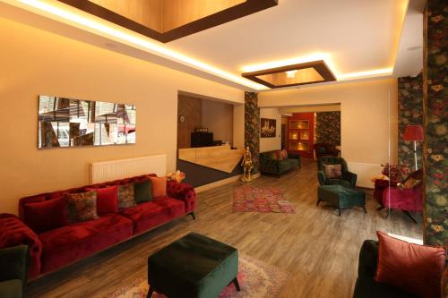 uma sala de estar com um sofá vermelho e cadeiras em Hisarhan Otel em Amasya