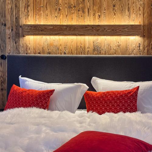 a bed with red and white pillows on it at activechalets six.nine.eight in Reit im Winkl