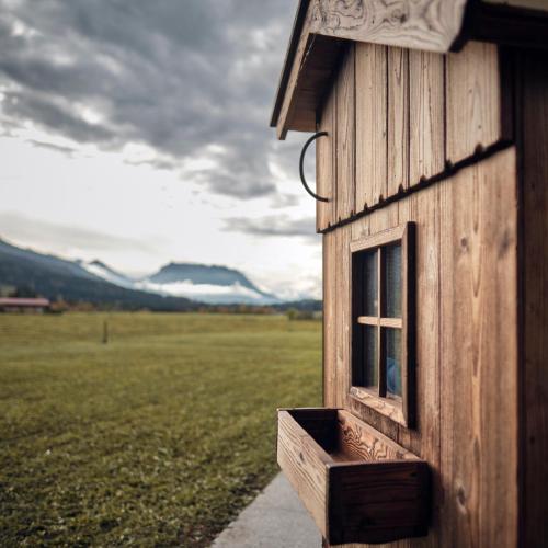 a building with a window on the side of a field at activechalets six.nine.eight in Reit im Winkl